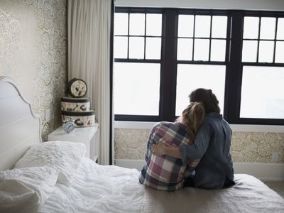 Mother consoling daughter on bed